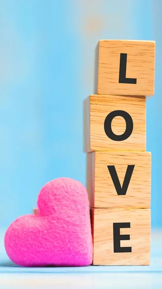 Wooden Cubes With Pink Heart Shape Decoration On Blue Table Background